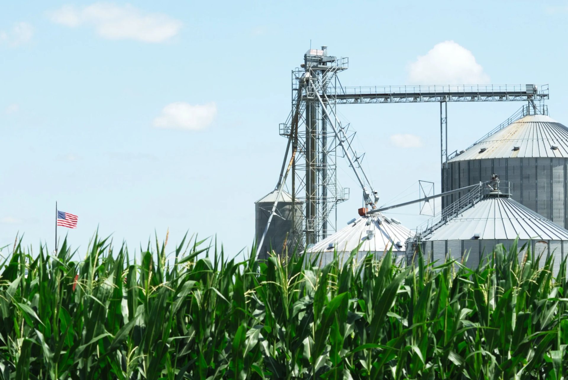 Grain storage bins beside an American flag on a farm