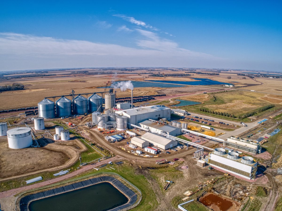 Aerial view of a biofuel plant with grain bins, tanks, and rail sidings